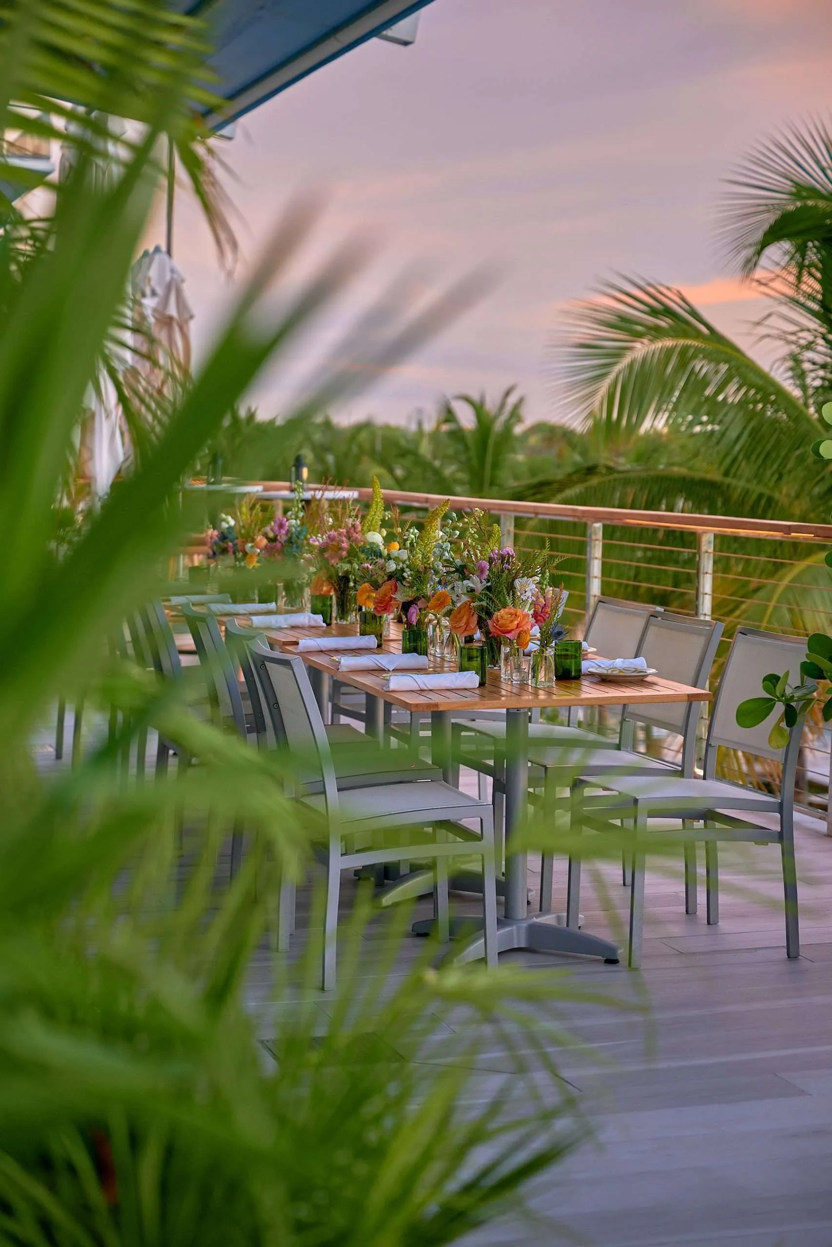 Rooftop event dinner at sunset framed by palms